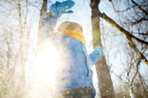 Preview: Little boy throwing fresh snow from his hands. Child enjoy walking in the park on snowy day.