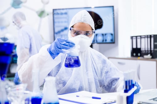 Preview: Researcher in protective suit holding a container from which comes a white smoke