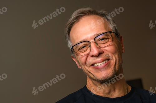 Preview: Smiling middle-aged male with glasses on a brown background