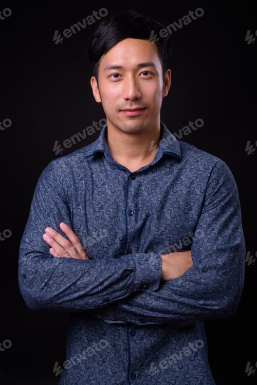 Preview: Young handsome Asian businessman against black background