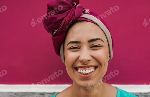 Preview: Young african woman smiling on camera outdoor while wearing traditional dress and turban