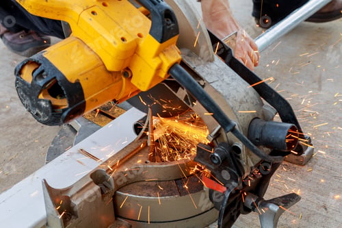 Preview: man, worker using a sliding compound mitre saw with circular blade for cutting meta