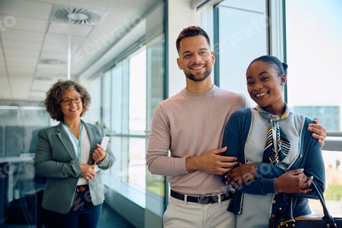 Preview: Happy multiracial couple in the office of their financial advisor looking at camera.