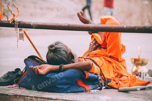 Preview: monk in bright orange clothing resting in Varanasi, India
