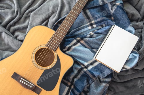 Preview: Acoustic guitar and notepad on a plaid background, top view.