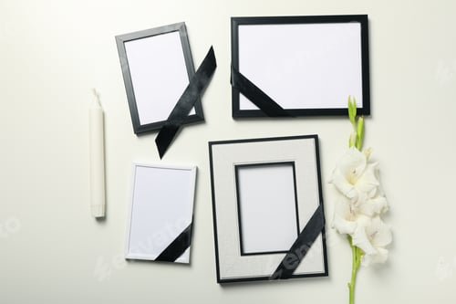 Preview: Photo frames with black ribbons, flower and candle on white background, top view
