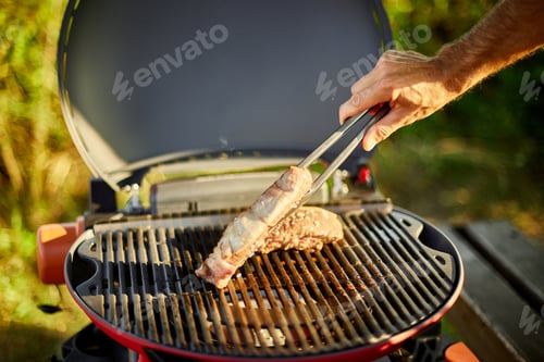 Preview: Man roasted meat on the gas grill on barbecue grill outdoor in the backyard