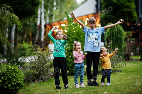 Preview: Four kids with doughnuts at evening yard. Tasty yummy donut food.