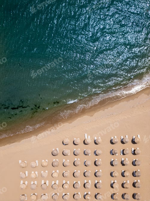 Preview: Aerial top-down view of a sandy beach with straw parasols and sunbeds aligned in rows