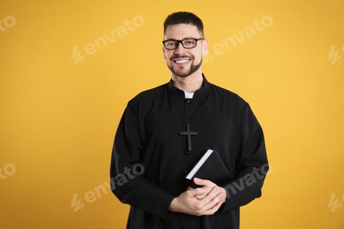 Preview: Priest in cassock with Bible on yellow background