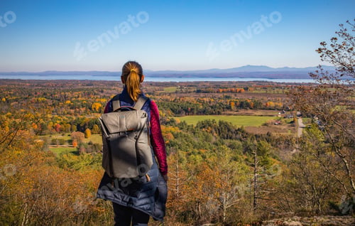 Preview: Woman on a hike looking out from atop a mountain at the beautiful fall countryside below