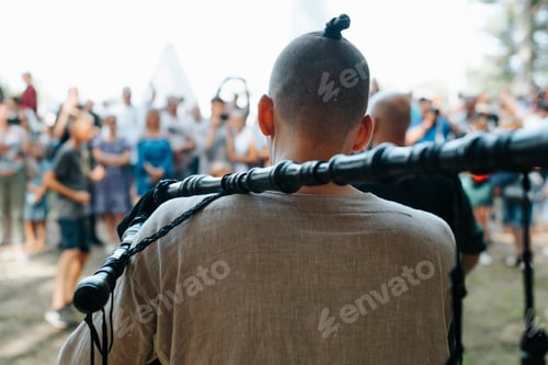 Preview: Folk concert outdoors. Back view of a male musician in a medieval costume playing