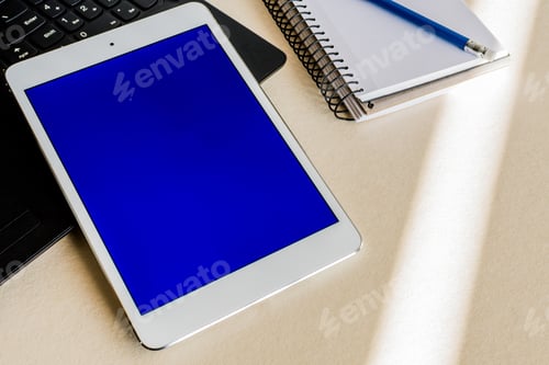 Preview: Tablet with blue screen on the keyboard of a laptop on a desk - technology and business concept
