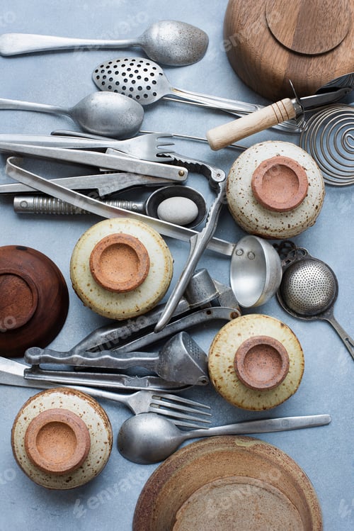 Preview: Assortment of vintage kitchen utensils and rustic pottery on a blue background