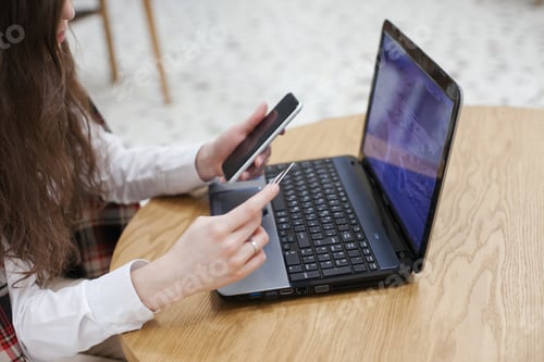 Preview: Woman shopping online using laptop, credit card and mobile phone on the table at cafe or office