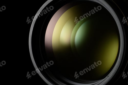 Preview: Close-up of a camera lens with green and yellow reflections close-up.