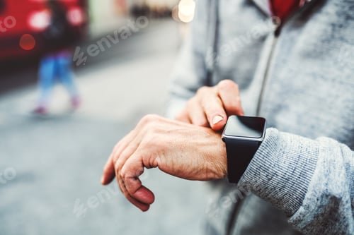 Preview: A close-up of unrecognizable man standing outdoors in city, using smartwatch.