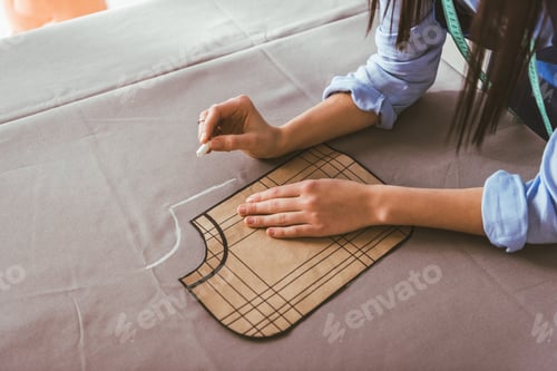 Preview: cropped image of seamstress making pattern with piece of chalk on fabric