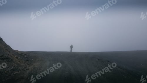 Preview: A person is standing on a rocky hillside in the rain