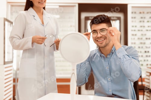 Preview: Optometrist helping young guy to choose correction glasses