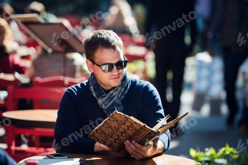 Preview: Young handsome man looking at the menu outdoors