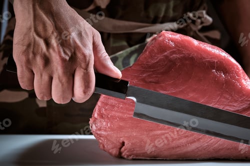 Preview: Male hands of a chef cutting a delicious loin of fresh bluefin t