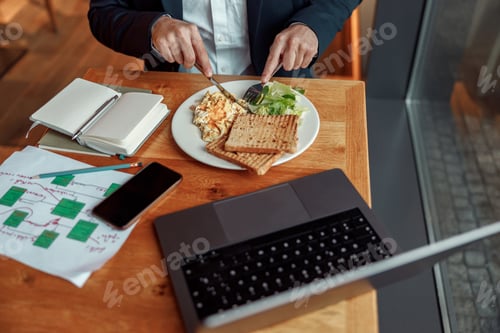 Preview: Close up of businessman taking a breakfast before starting working day in cafe