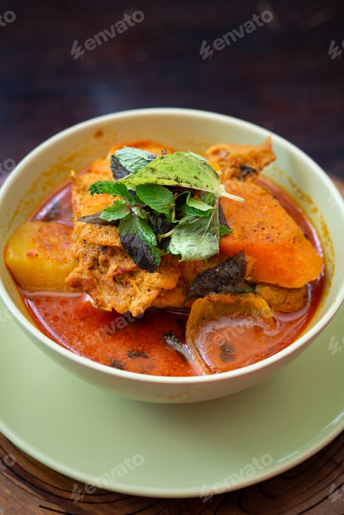 Preview: Chicken curry in a green bowl on a wooden base background.