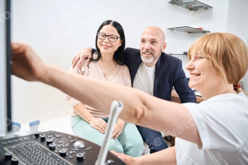 Vista previa: Médico ginecólogo positivo que muestra la primera imagen del feto a una pareja feliz