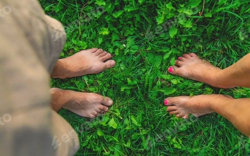 Preview: Legs of a woman and a man on the grass. Selective focus.