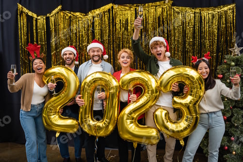 Visualização: Empresários inter-raciais alegres segurando champanhe e balões em forma de 2023 no escritório