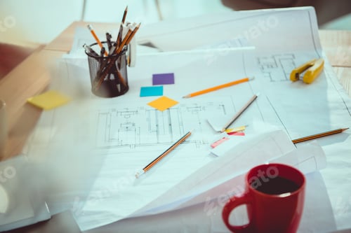 Preview: Close-up view of various office supplies, coffee cup and blueprints on office table