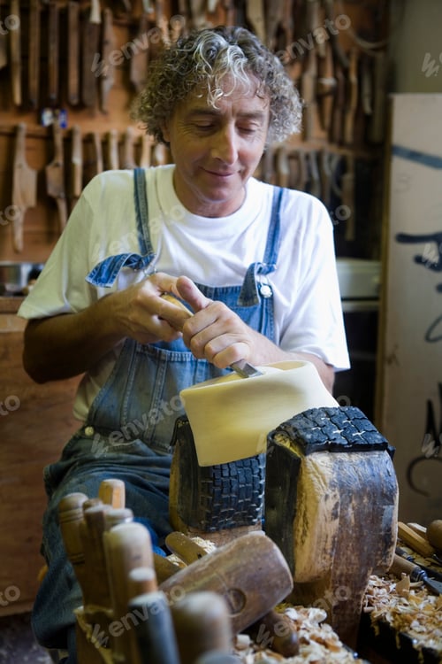 Preview: Carpenter using chisel on wooden mould for headwear in workshop