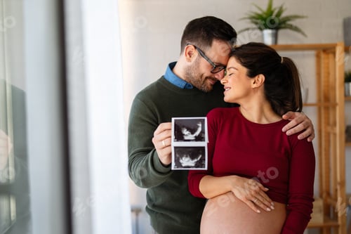 Preview: Woman and her boyfriend holding up an image of her sonogram of the baby. New family, love, baby
