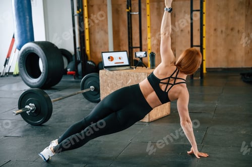 Preview: View from the back. Shooting video by smartphone. Beautiful strong woman is in the gym