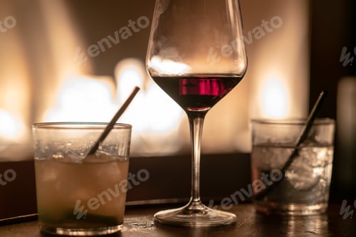 Preview: Close up of glasses of vodka, rum and red whine against fire pit
