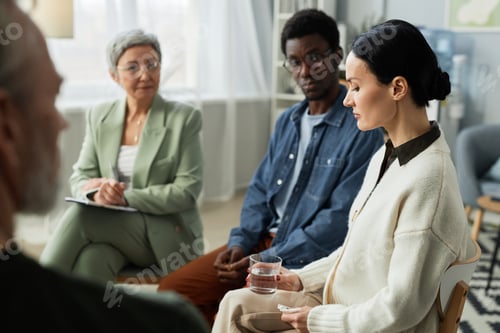 Preview: Side view of stressed brunette woman sharing her problems with support group