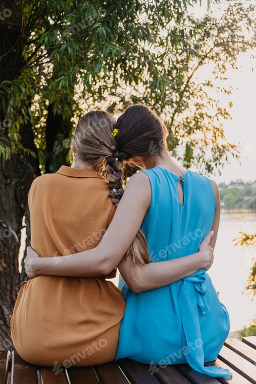 Preview: Two women embracing at sunset near the water