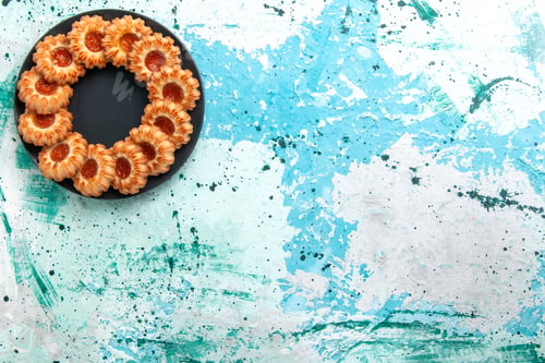Preview: top view delicious cookies round formed with jam inside black plate on the light blue background