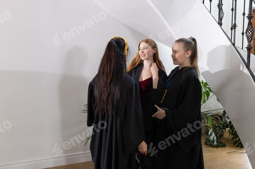 Preview: Teen graduates in gowns celebrating and chatting happily at school ceremony