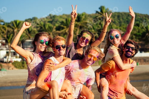 Preview: mixed race friends having fun with colors on seaside outdoors in Goa India