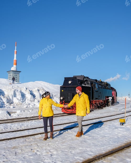 Preview: couple of men and women watching the steam train during winter in the snow in the Harz Germany
