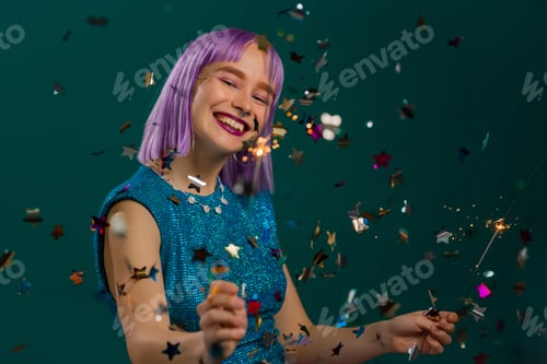 Preview: Hipster woman with sparkling bengal fire dancing under confetti rain on green background. Christmas