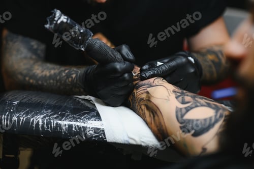 Preview: Tattoo salon. The tattoo master is tattooing a man.