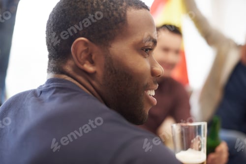 Preview: Over the shoulder view of man holding glass of beer looking away smiling