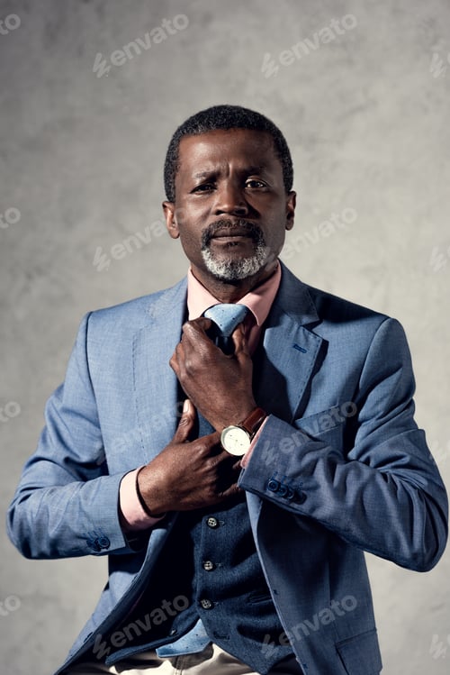 Preview: confident middle aged african american businessman fixing tie