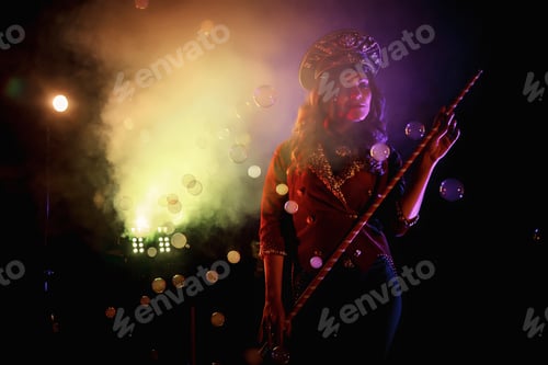 Preview: Woman magician illusionist of circus with cane showing soap bubbles show at black background