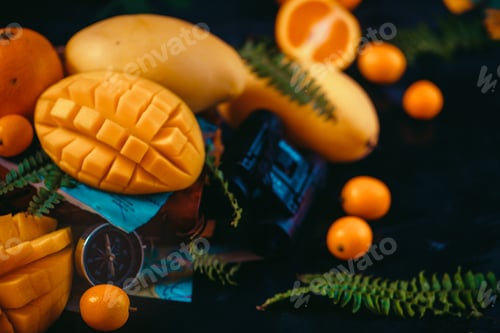 Preview: Cut mango halves close-up header with oranges, kumquat, and other tropical fruits. Dark background