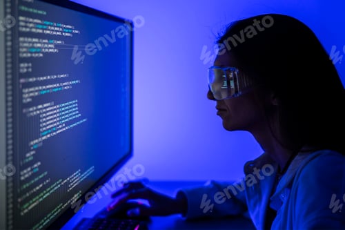 Preview: Female Software Developer Concentrating on Coding Project at Workplace During Nighttime