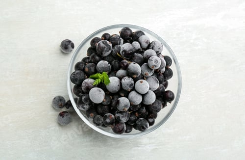 Preview: Tasty frozen black currants on white table, flat lay